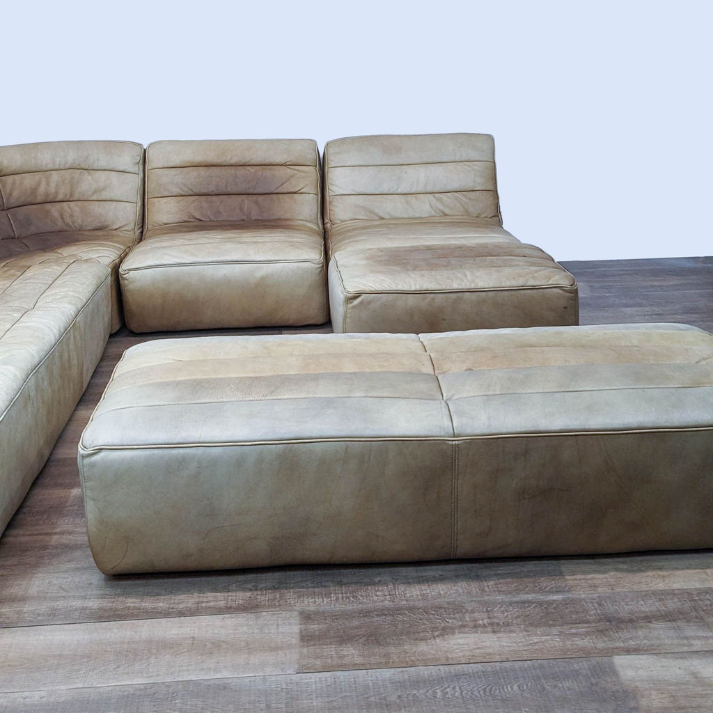 Brown leather modular sectional with a worn texture on wooden floor.