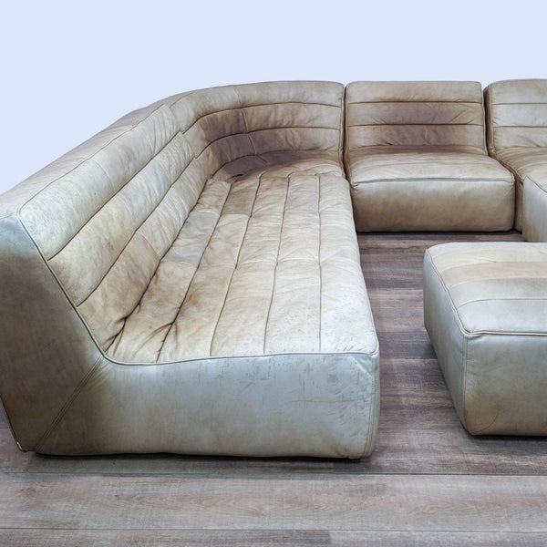 A modular sectional with worn tufted leather on wood flooring.