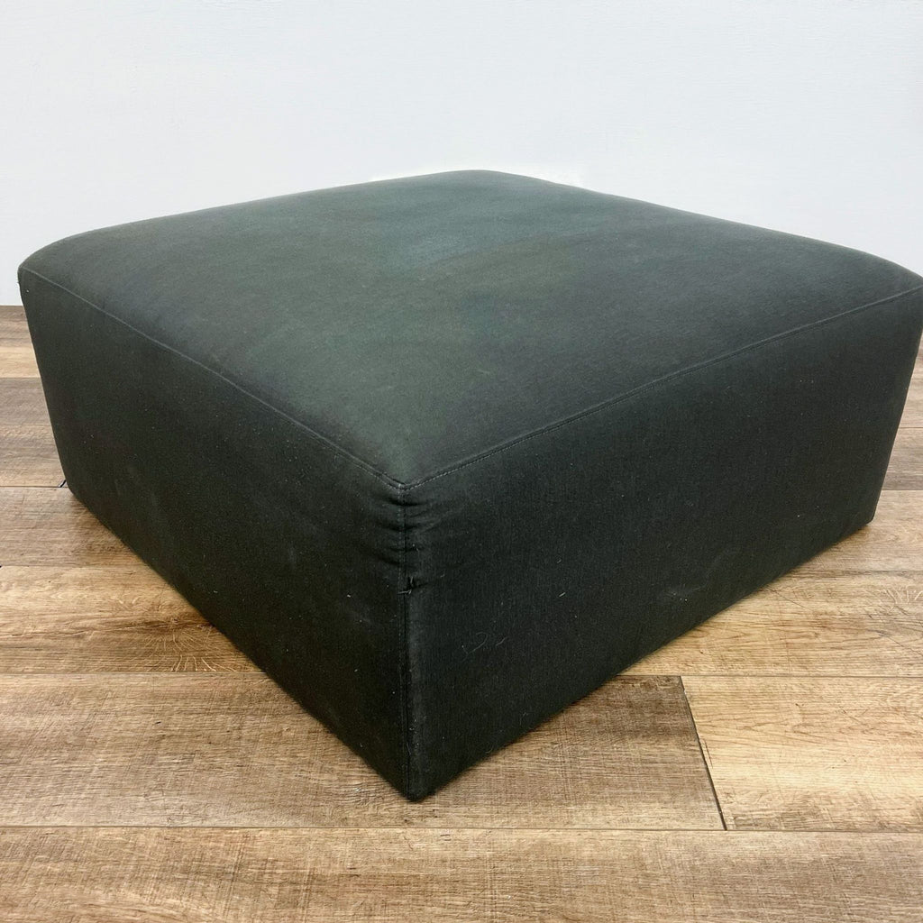 a black leather ottoman with a thick fabric