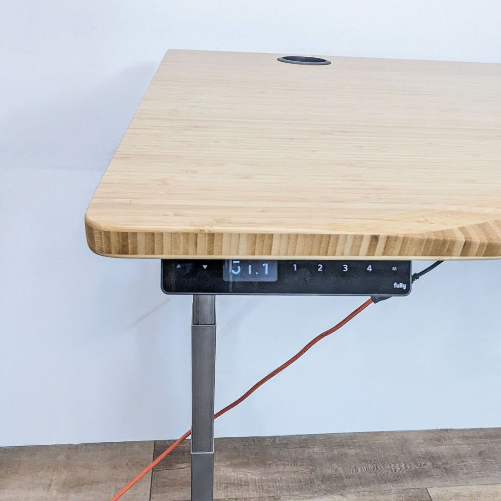 Close-up of the bamboo desk edge with digital height control panel and surge protector.