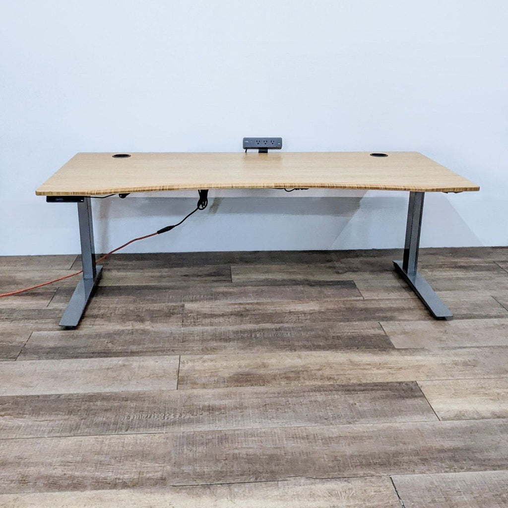 Bamboo desk with motorized height adjustment and a mounted surge protector.