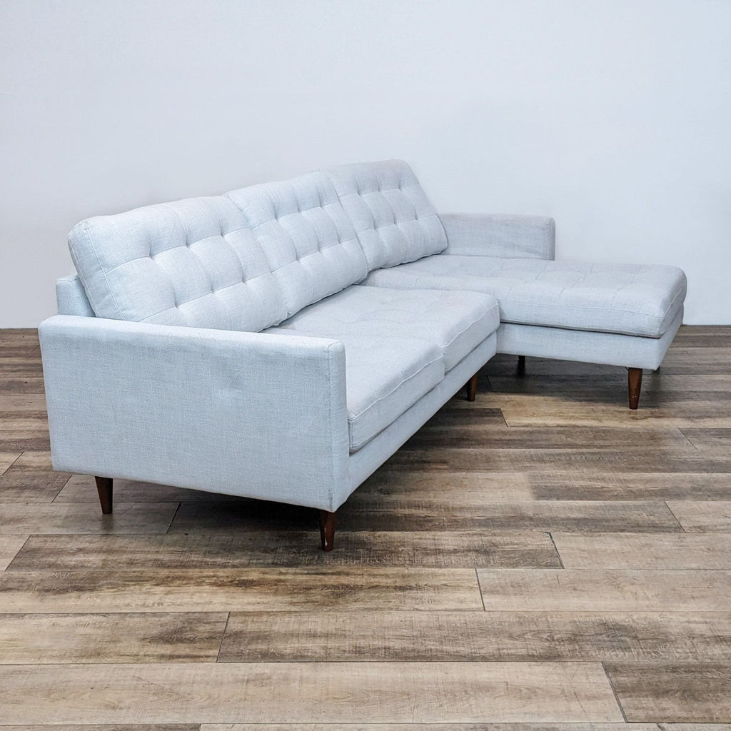 Light gray two-piece sectional with tapered wood finish legs.