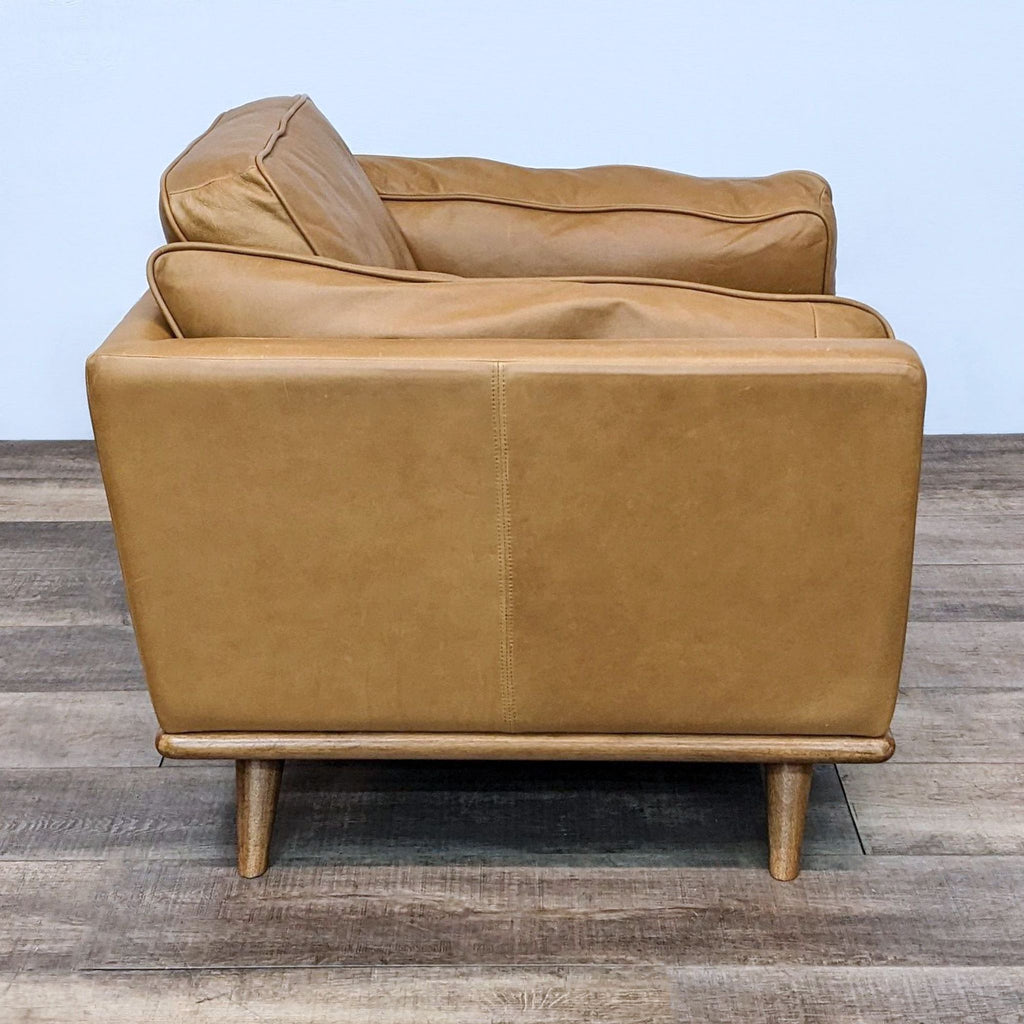 Side view of a mid-century modern style lounge chair featuring oak wood and leather, by Article.  