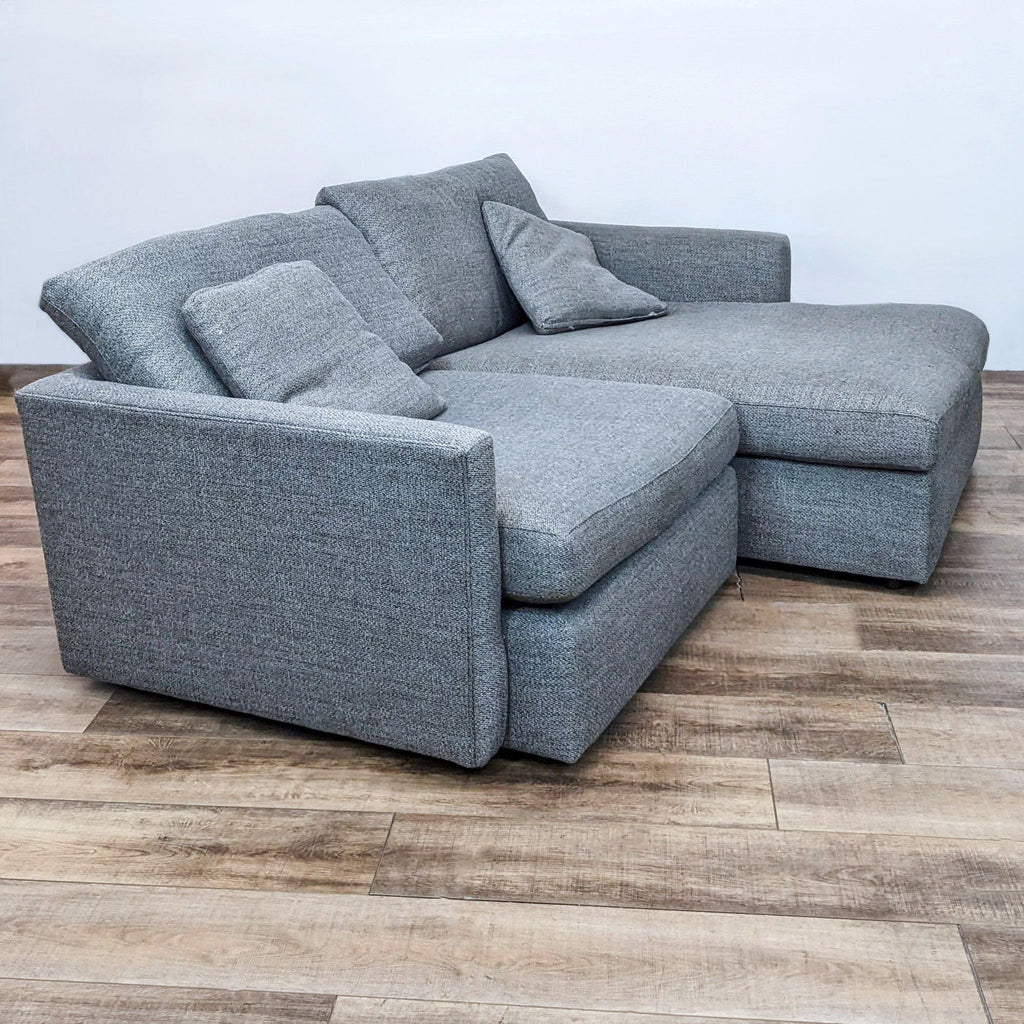 Side view of a gray Crate & Barrel sectional with deep cushions and narrow track arms.