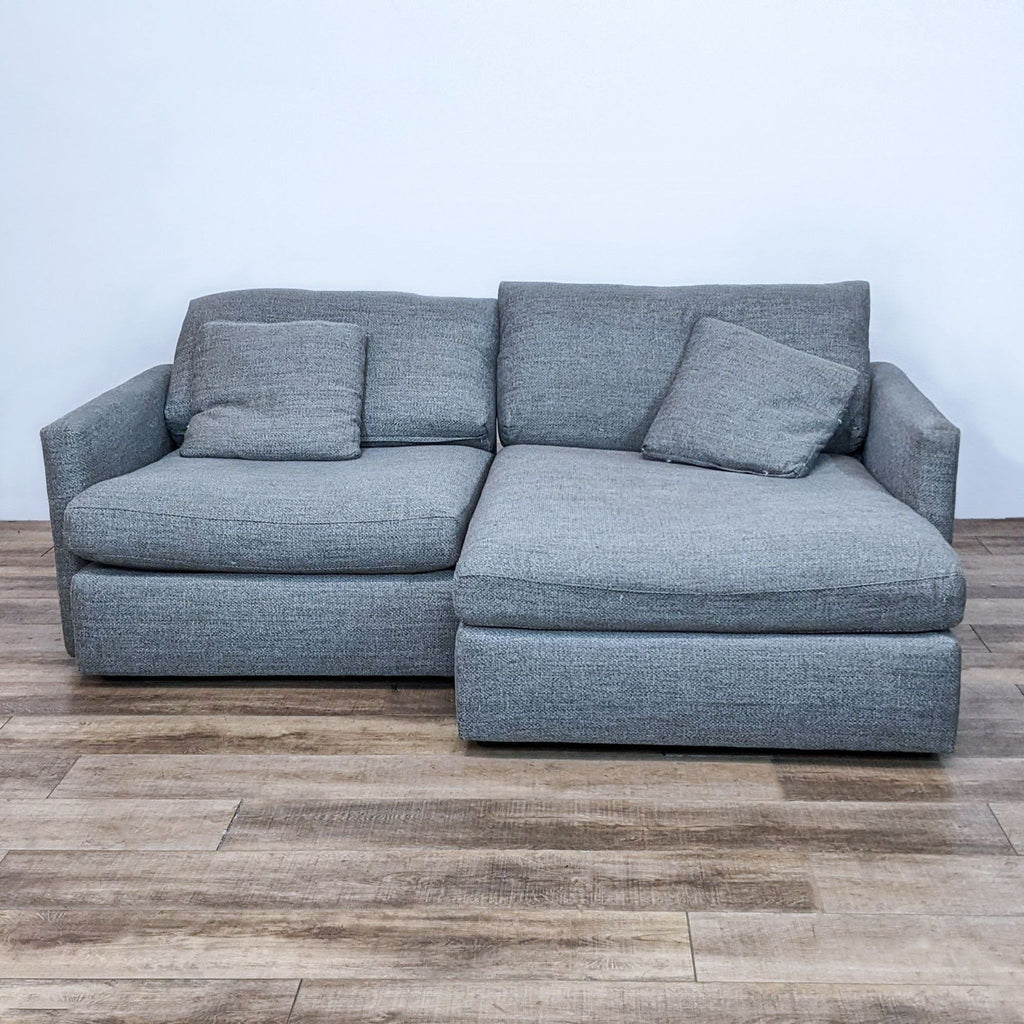 Gray two-piece sectional with narrow arms, featuring plush cushions, by Crate & Barrel.