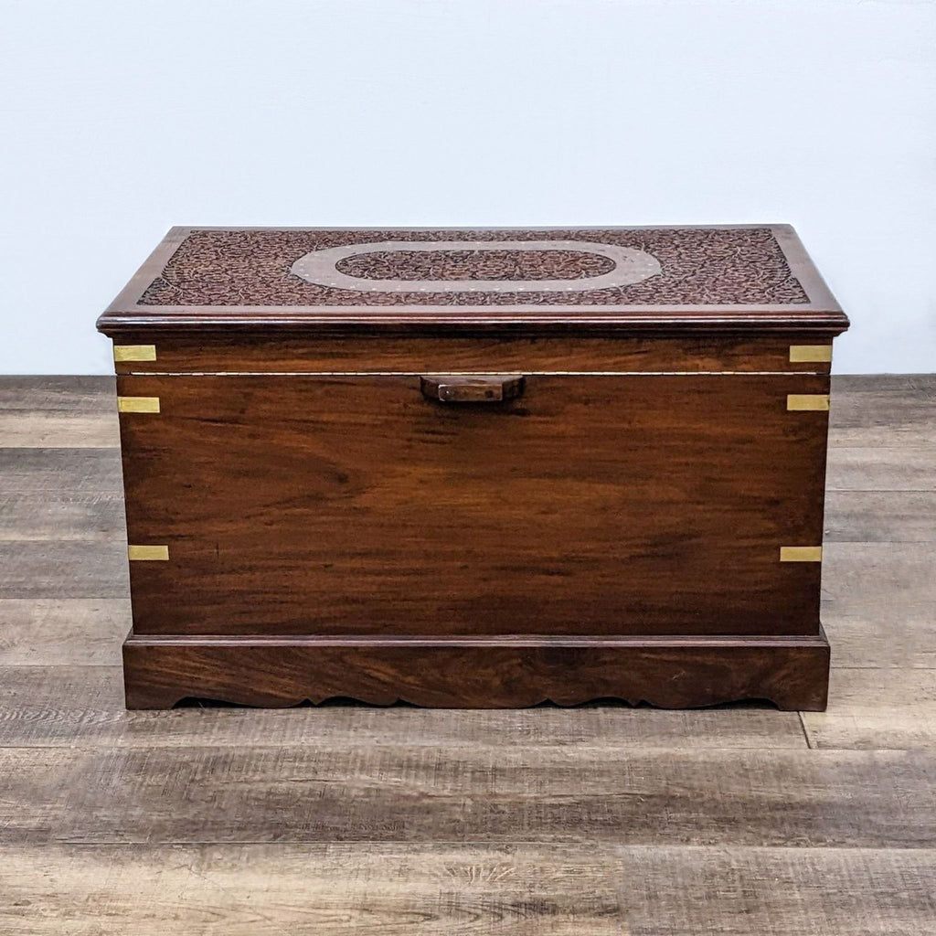 Reperch-brand wooden trunk with brass hardware and patterned inlay on lid, closed, on a wooden floor.