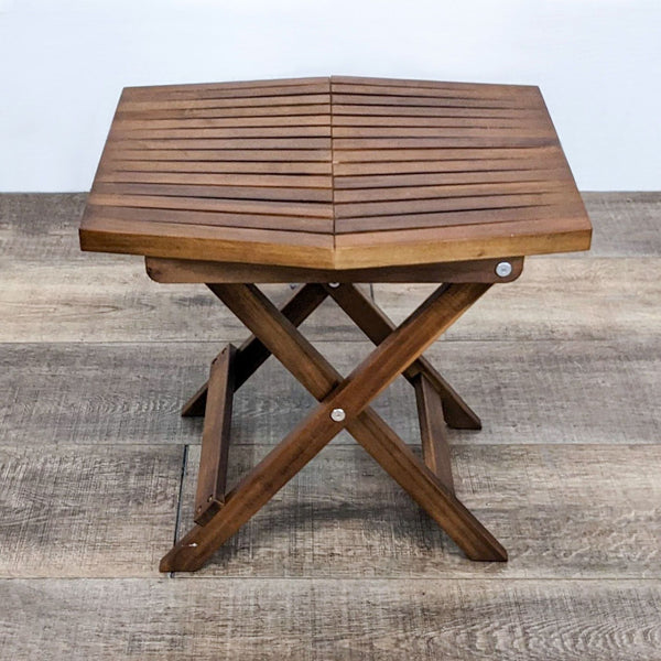 Solid teak folding table with a slate wood design, shown fully opened on a wooden floor.