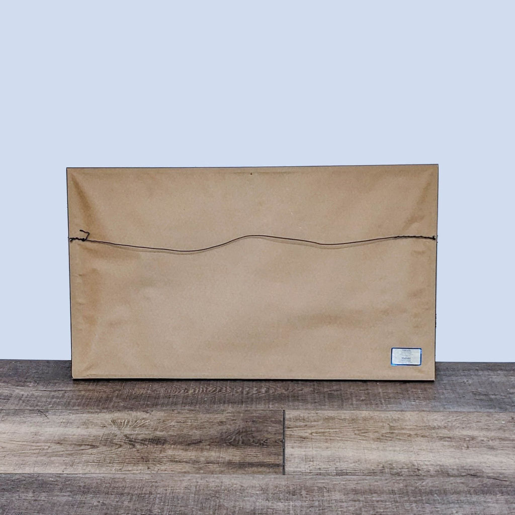 Back view of framed embroidered artwork with hanging wire.