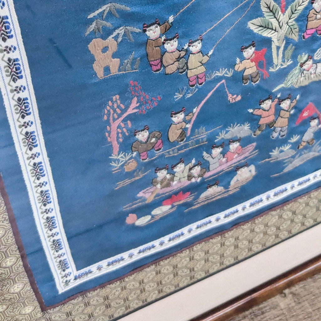 Close-up of Asian embroidery on blue fabric with water scenes.