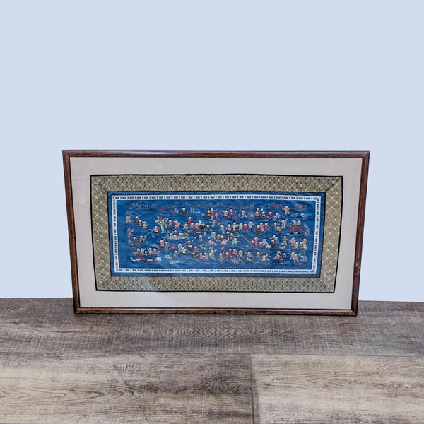 Framed blue fabric art depicting people enjoying water activities.