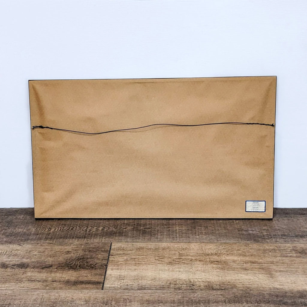 3. Back of framed art with hanging wire and label at the bottom corner.