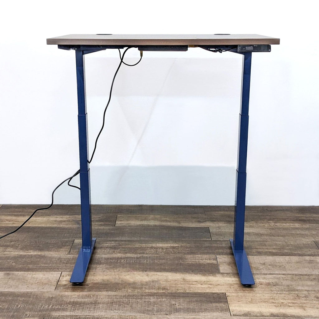 Height-adjustable desk with dark wood top and blue metal legs.