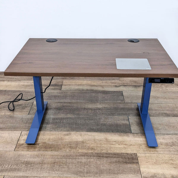 Dark wood desk with blue steel frame and motorized height adjustment.