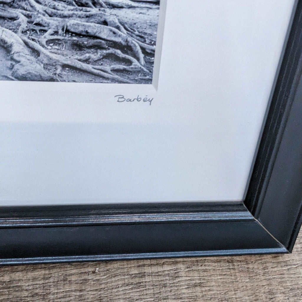 Close-up of Barbey's signature on "Stumped," depicting intertwined tree roots and architectural elements.