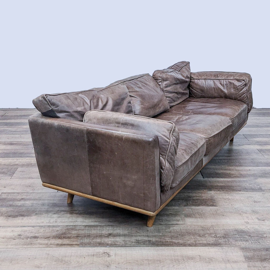 Worn leather 3-seat sofa with solid wood frame, viewed from an angle.