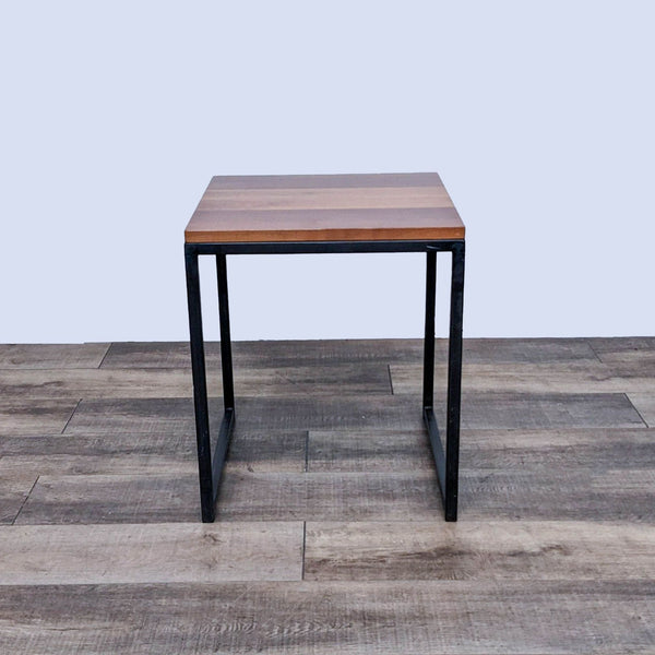 Reperch end table with a wooden square top and sleek black metal legs.