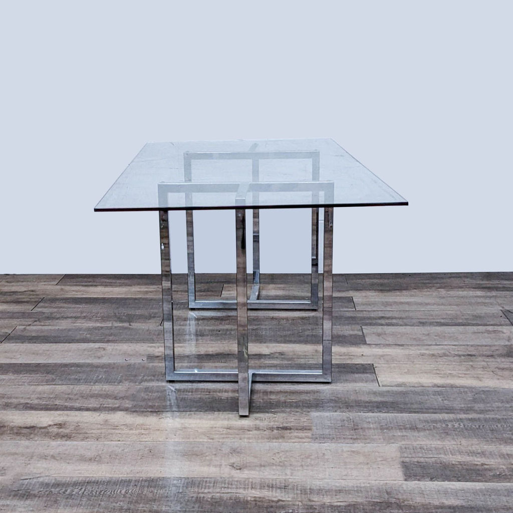 Elegant glass dining table by CB2 featuring a chrome-plated base.