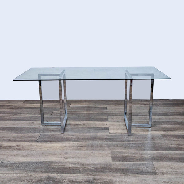 CB2 Silverado dining table with chrome base and glass top on wood floor.