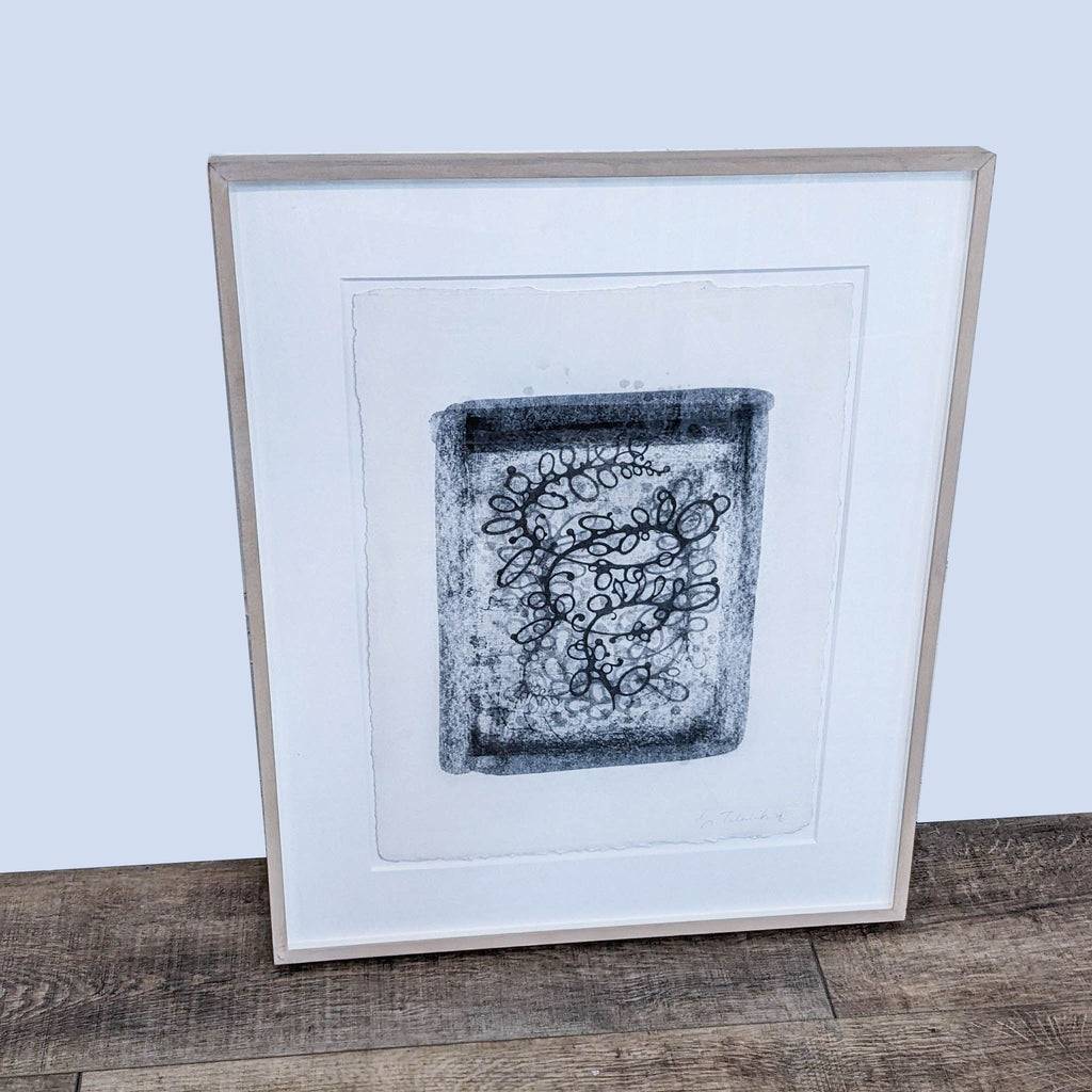Abstract framed print by Reperch showing swirling line design. Wood floor background.