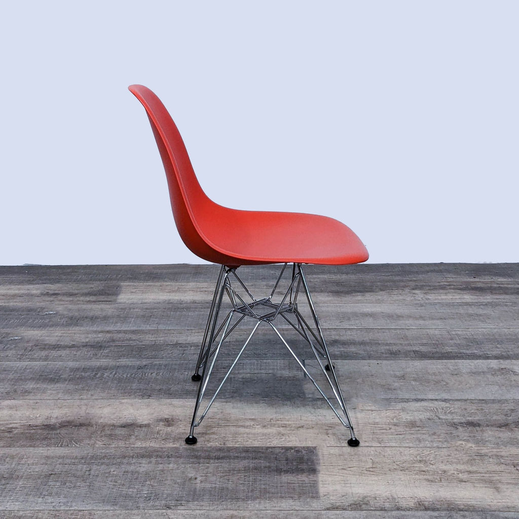 Side view of a red molded Eames chair with metal Eiffel base.  