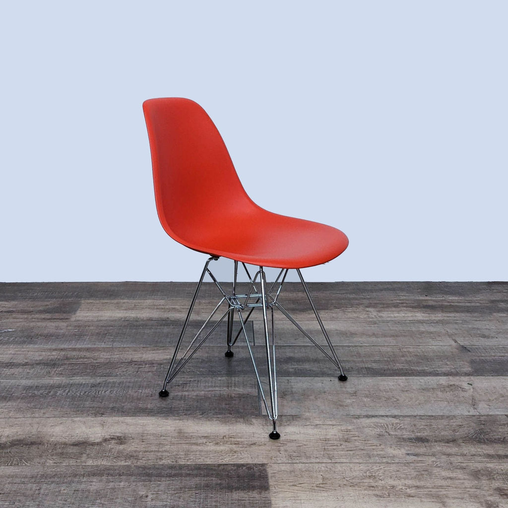 Angled view of a red Herman Miller Eames chair with a plastic seat.
