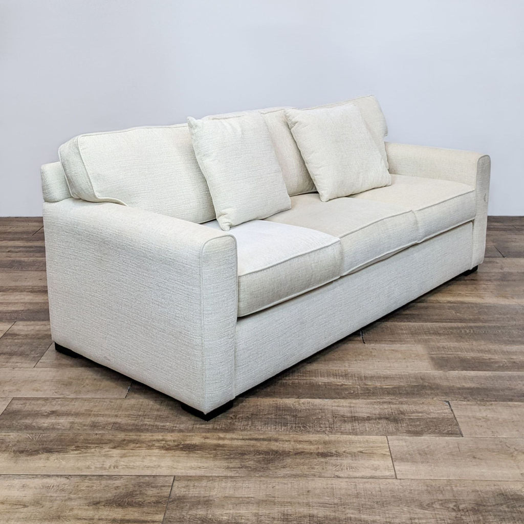 2. Angled view of a clean line off white sofa with T-back design and curved arms by Living Spaces.