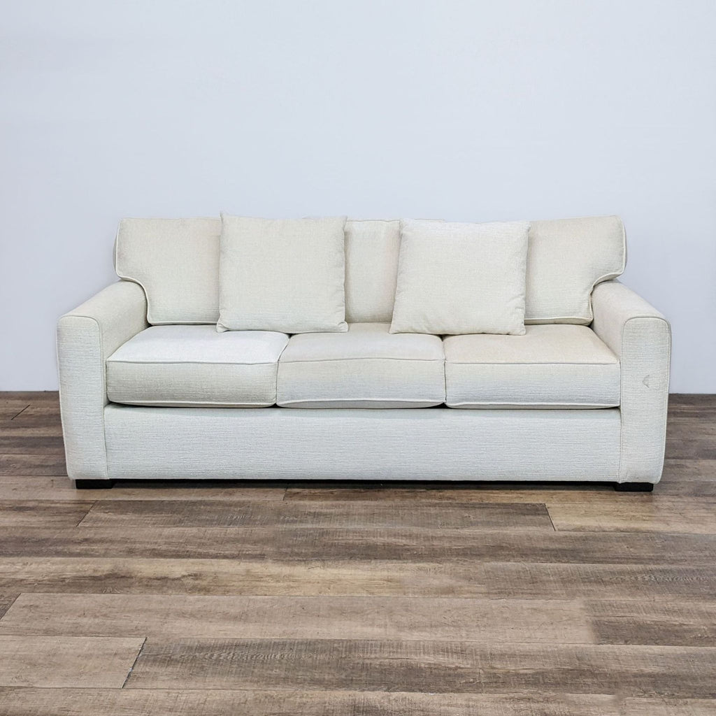 1. Off white 3-seat sofa with modern curved arms and three back pillows, from Living Spaces, on wood floor.