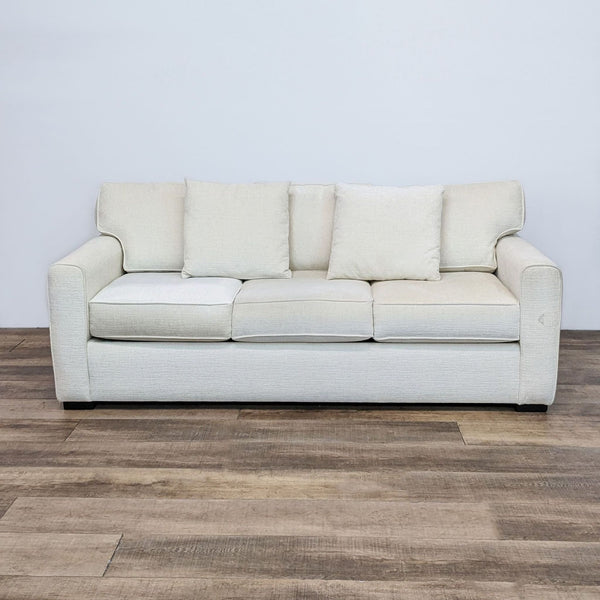 1. Off white 3-seat sofa with modern curved arms and three back pillows, from Living Spaces, on wood floor.