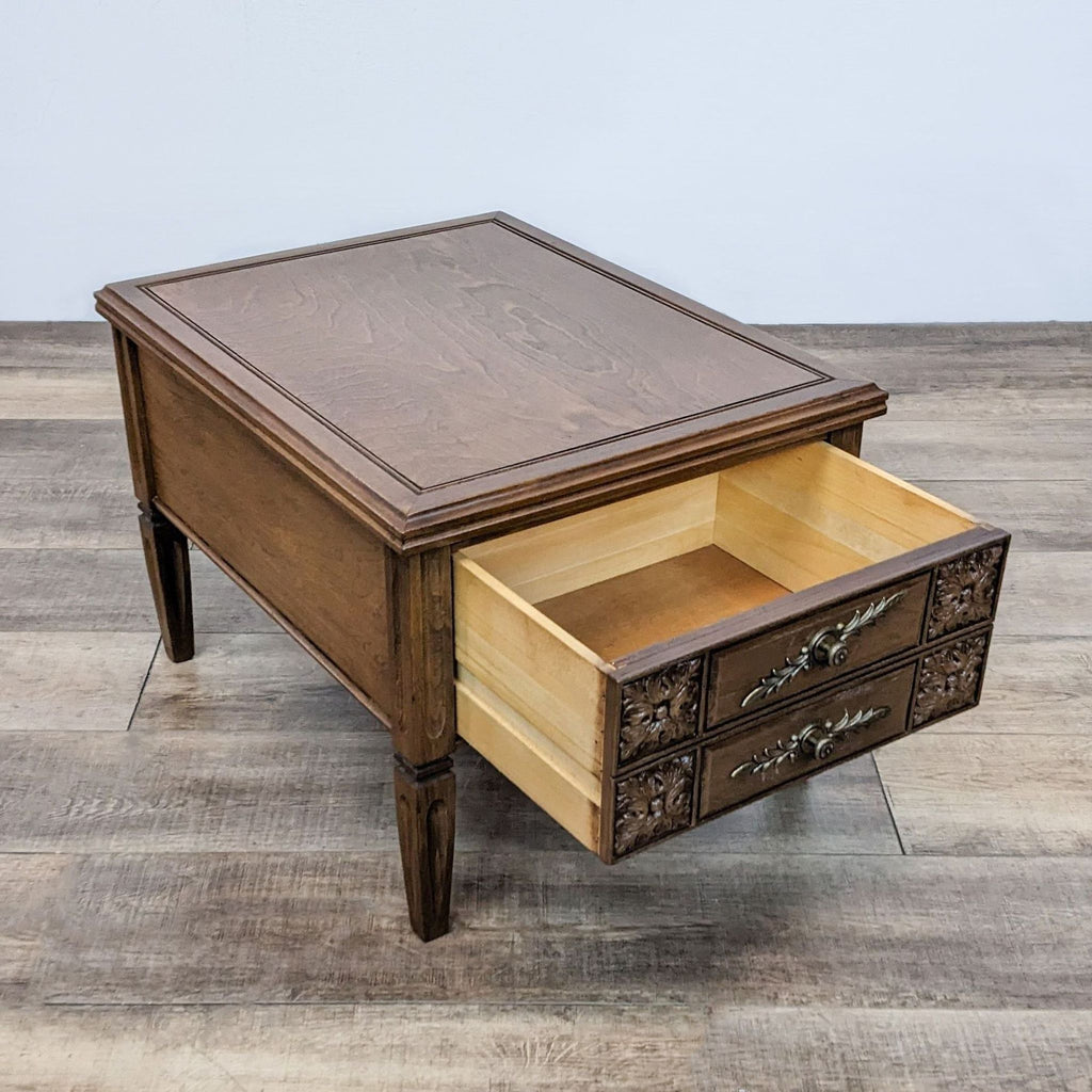 Classic end table with open drawer, detailed carvings, and metal handles.