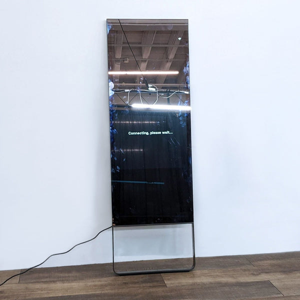 Lululemon Studio Mirror Model One displaying "Connecting, please wait" message in a gym setting.  