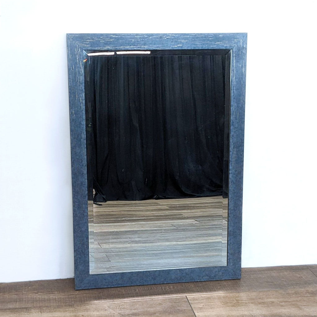 Mirror with weathered frame finish, showing a reflection and wood floor.  