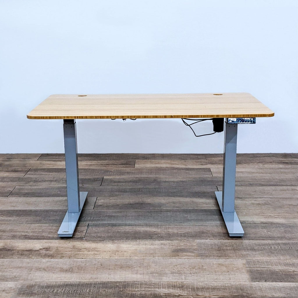 Minimalistic bamboo desk with gray steel legs and motorized height adjustment.