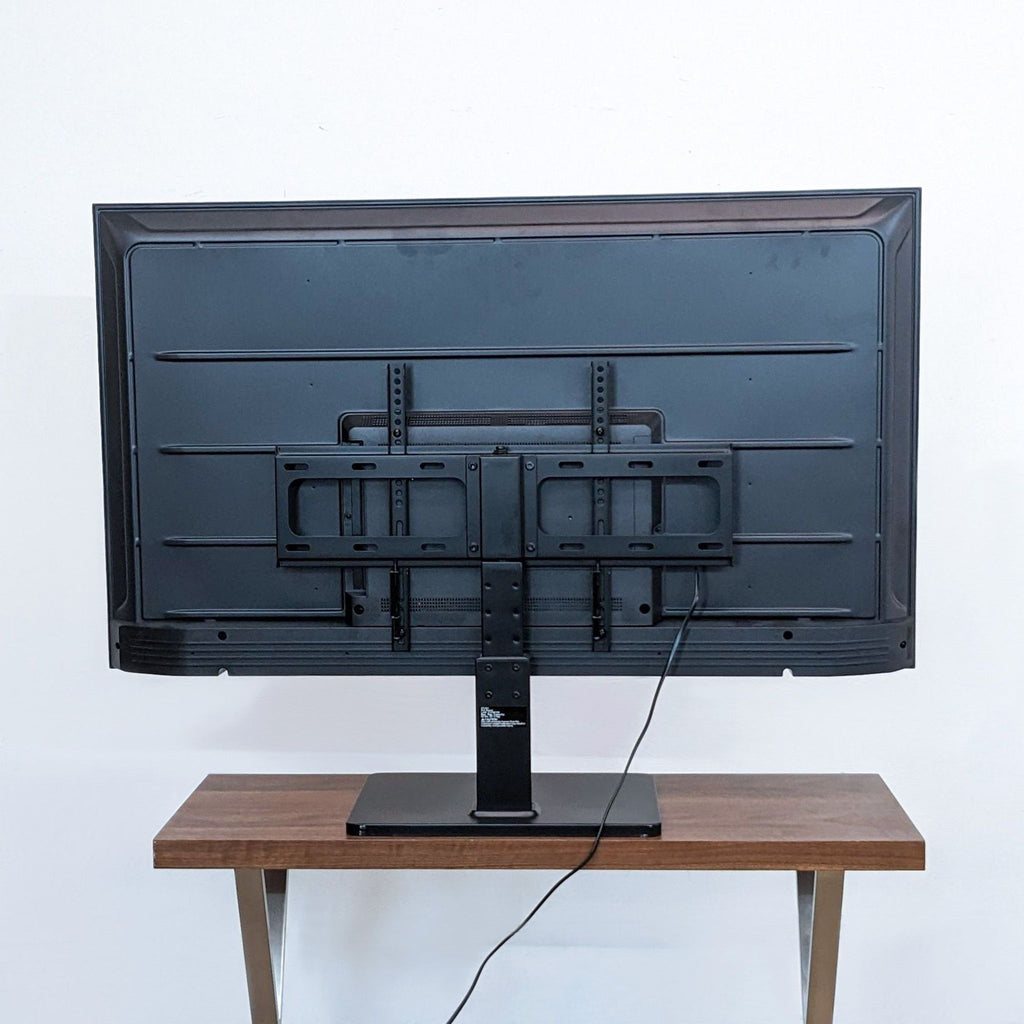 Back view of Amazon 55" Fire TV on a wooden stand showing the mount and cables.