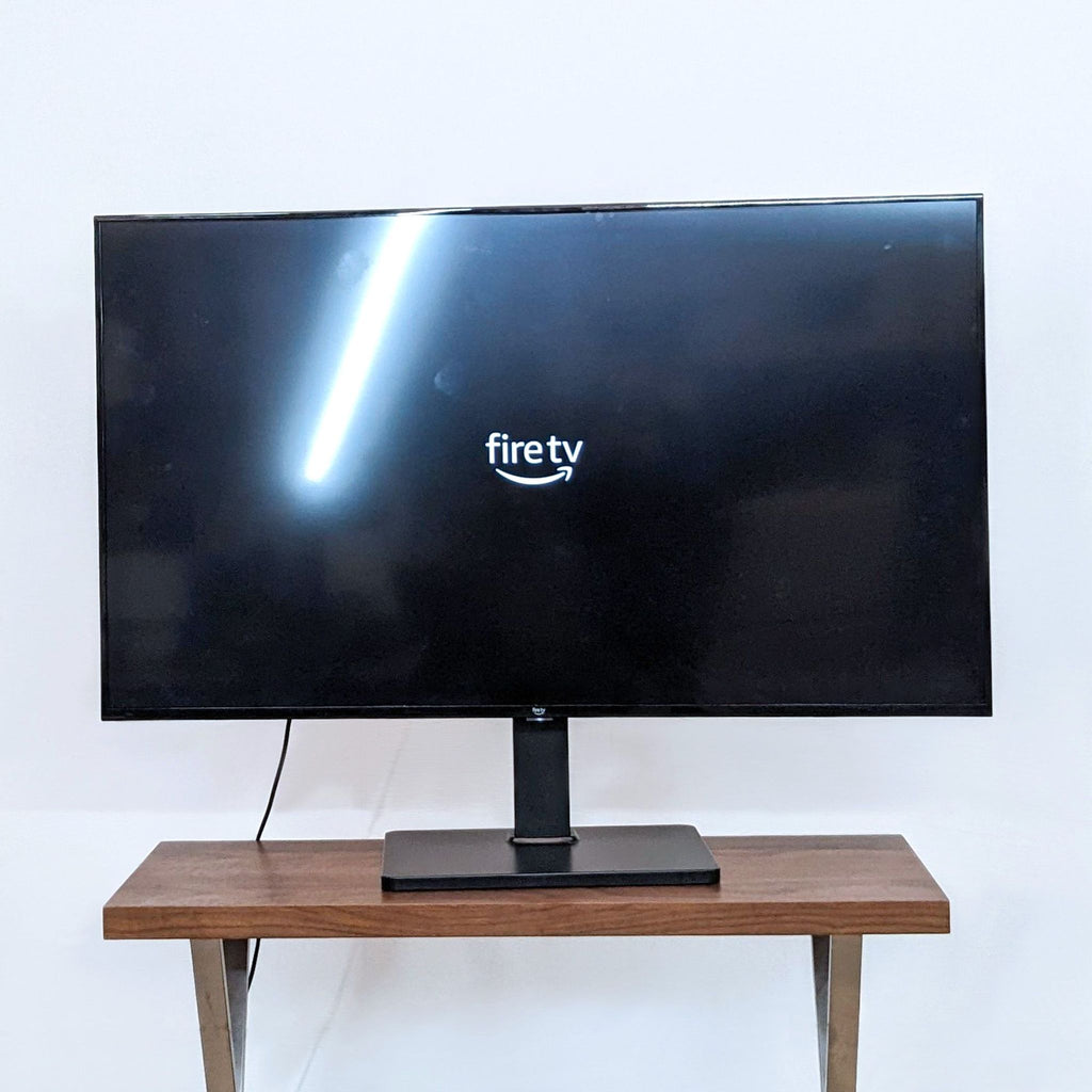 Amazon 55" Fire TV displaying the Fire TV logo on a wooden stand.