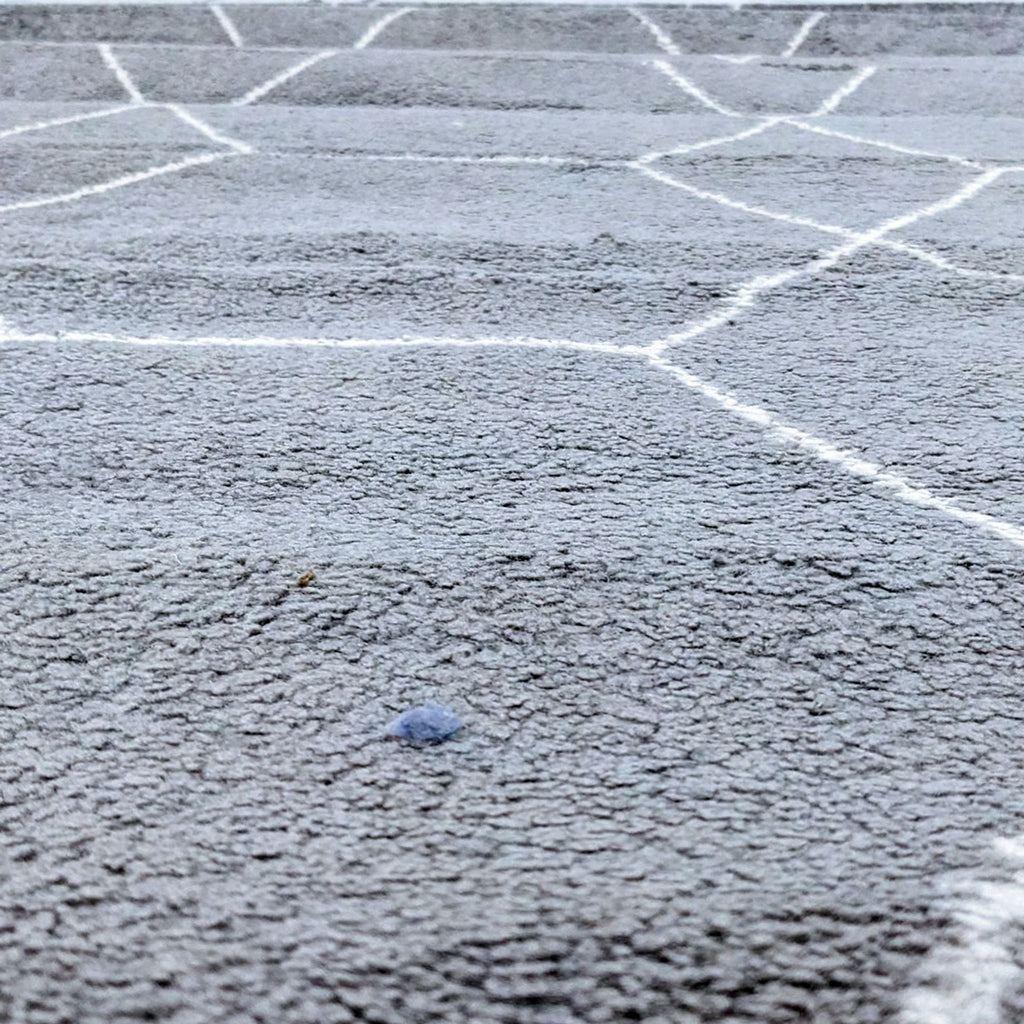 a close up of a grey carpet with a white painted pattern
