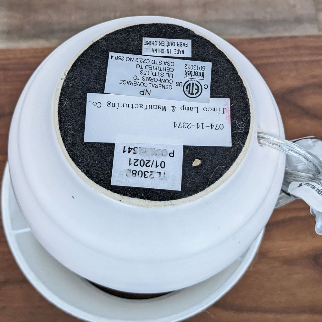 Bottom of Reperch lamp with visible labels and cord on a wood surface.