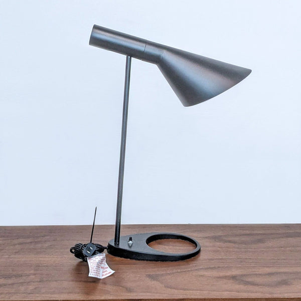 Sleek black desk lamp with conical shade on a wooden surface.