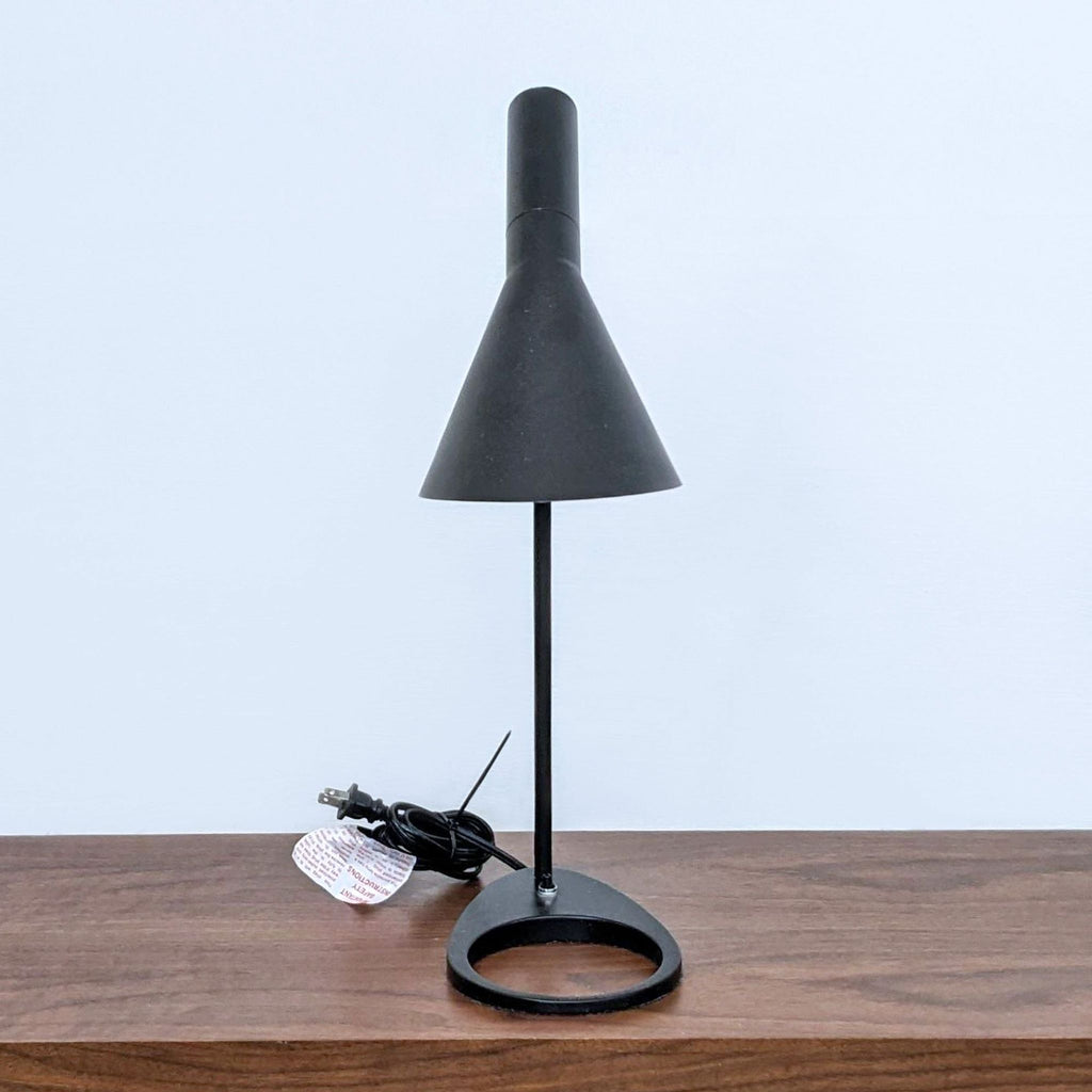 Side view of a modern black desk lamp with a round base.