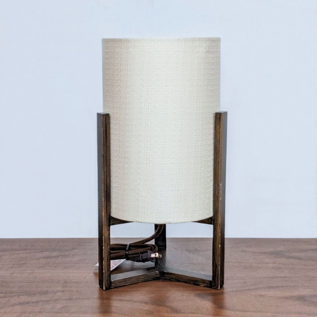Reperch lamp with a cylindrical beige shade and wooden base on a table.  