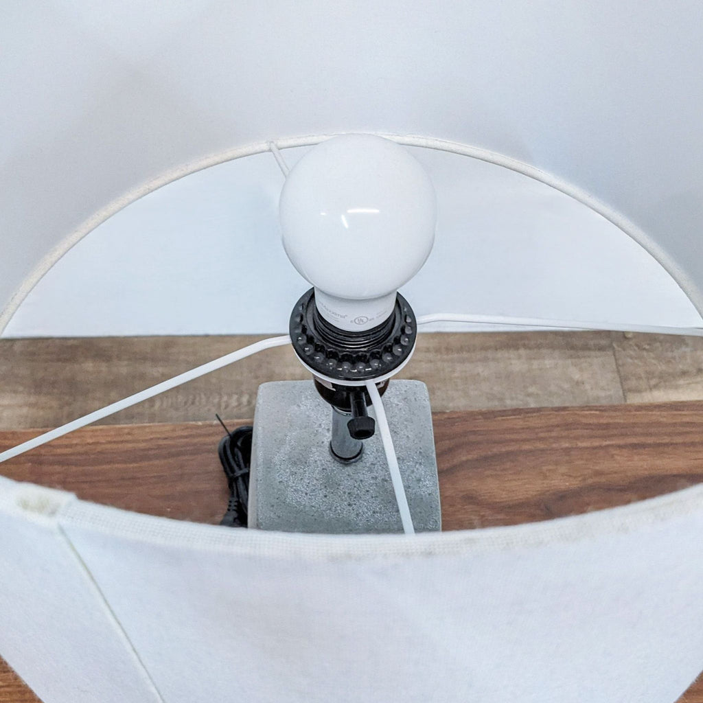 Top view of Reperch lamp showing bulb and white cylindrical shade from above.