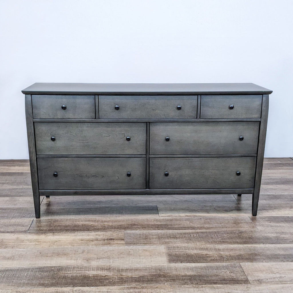 Front view of a smoky grey-brown 7-drawer dresser on wooden floor.