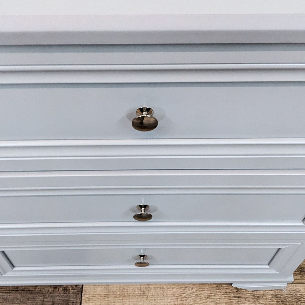 Close-up of dresser's metal knob pulls and drawer details.