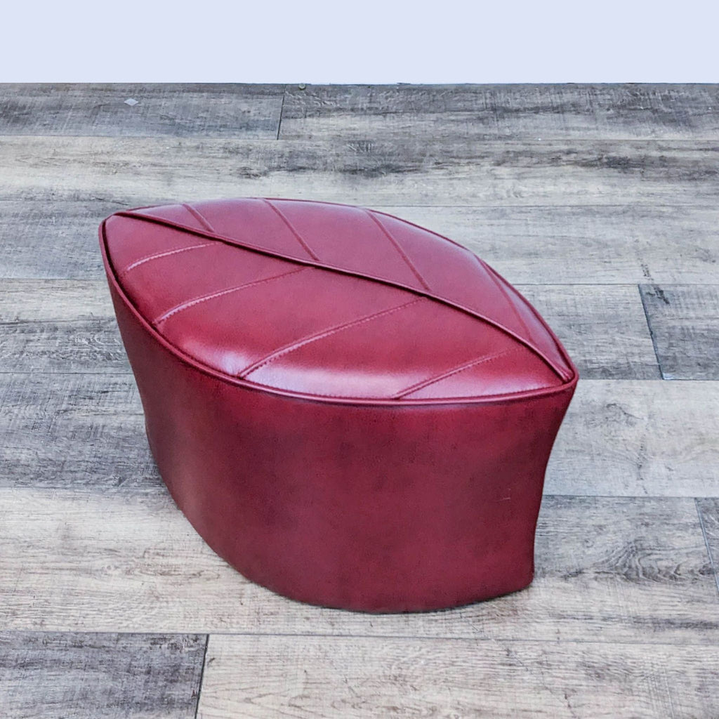 Contemporary red ottoman with leaf design from Reperch, placed on rustic flooring.