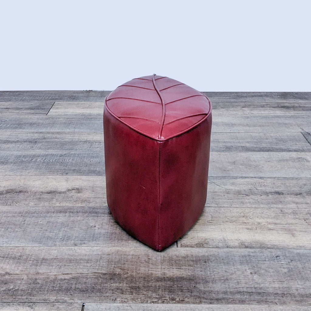 Leaf-inspired red leather ottoman by Reperch, set on a light wooden floor.