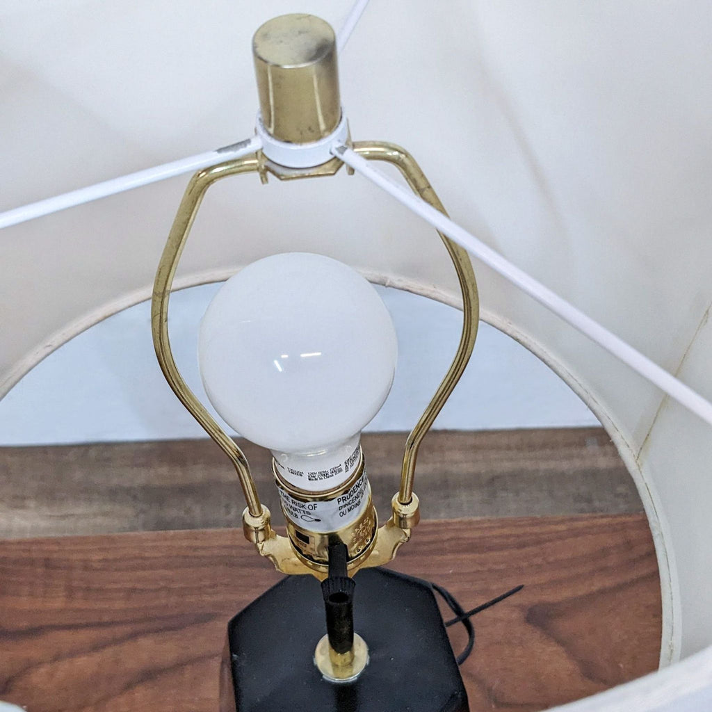 View of the inner structure of a Reperch lamp, showing a bulb and gold components.