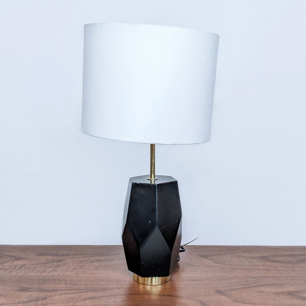 Reperch table lamp with a faceted black base and white shade on a wooden surface.
