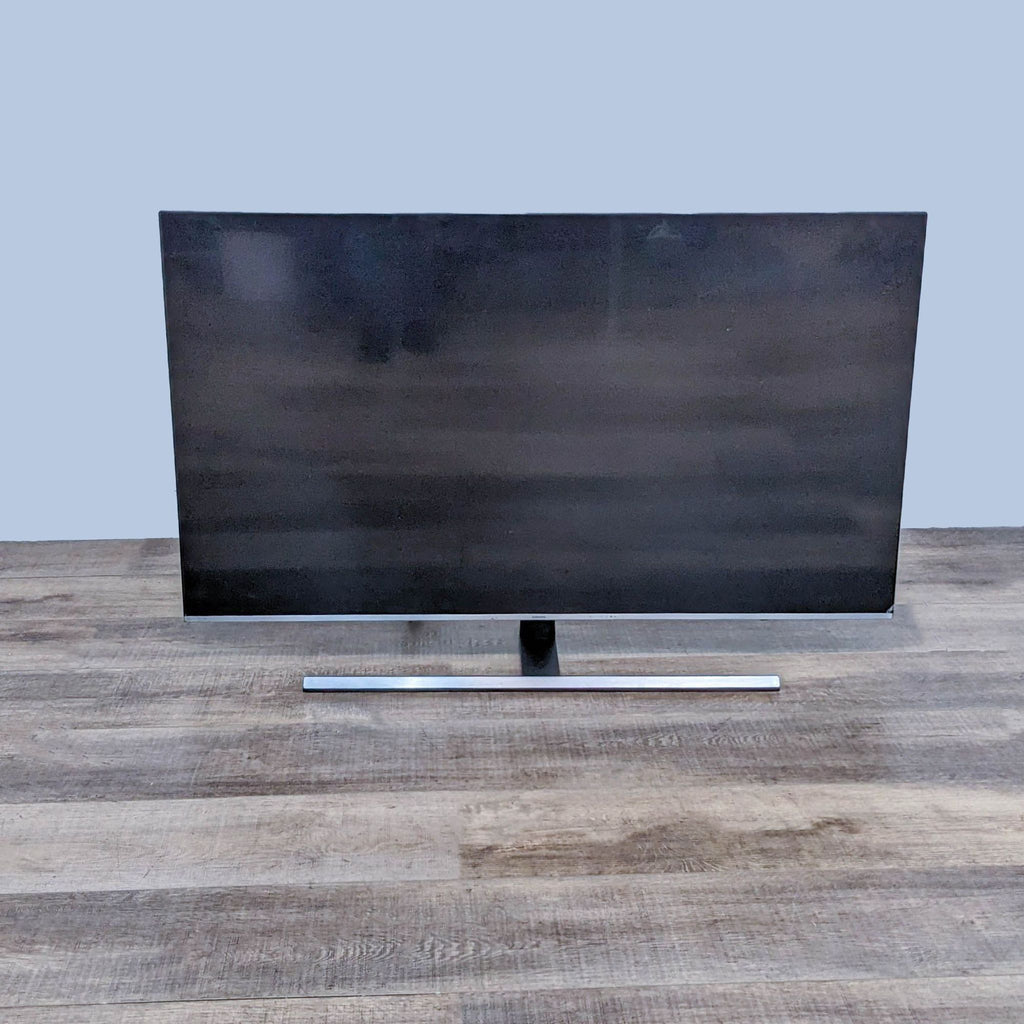 Samsung flat TV with a sleek design showcased against a light blue background.