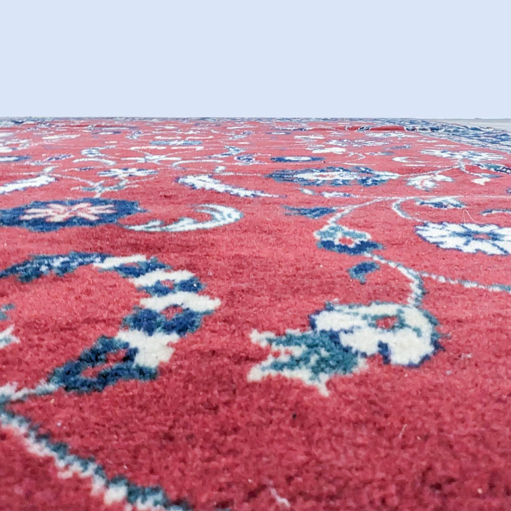 Close-up of a Reperch red oriental rug showcasing detailed floral motifs with blue accents.  