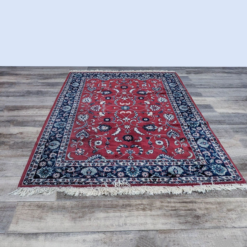 Reperch oriental wool area rug, red with floral designs and blue border, measuring 5'7" x 8'4".