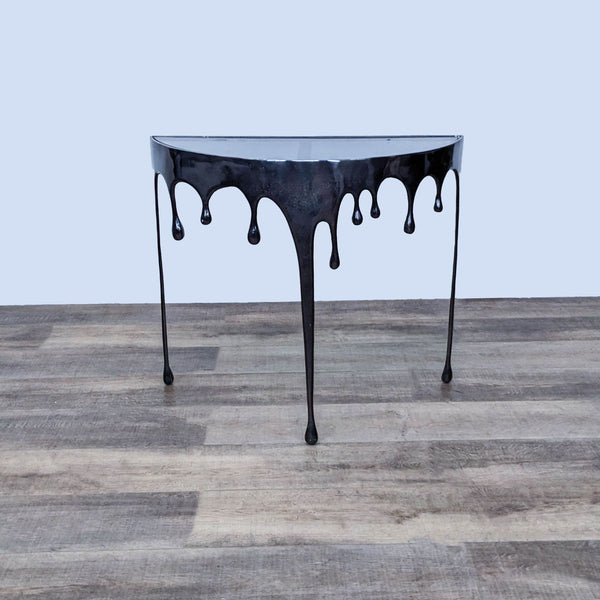 Black half-moon console table with drip design by Reperch on wooden floor. 